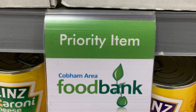Green and white label on Waitrose shelf indicating Cobham Area Foodbank priority item